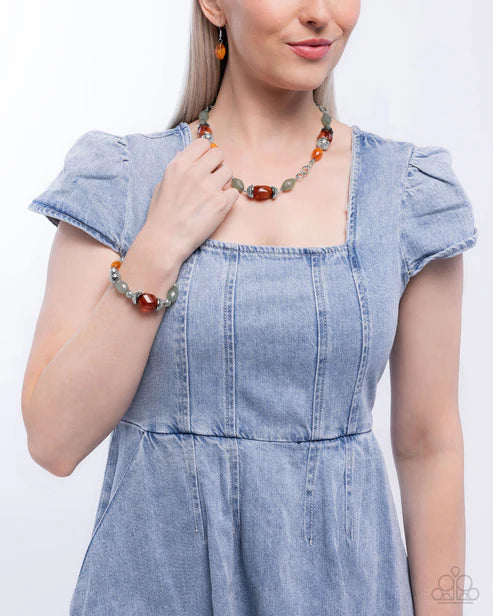 Woman wearing a blue dress with ruffled sleeves and a colorful necklace on a white background