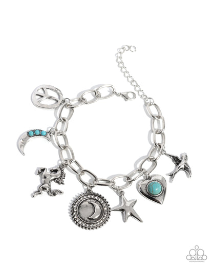 A silver-tone charm bracelet featuring multiple celestial and mystical charms, including a crescent moon with turquoise accents, a lion, a star, a heart, and a peace sign, displayed on a clean white background.
