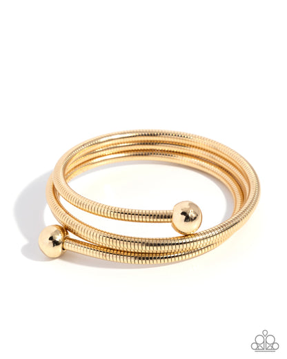 Set of gold bangles with spherical ends on a white background