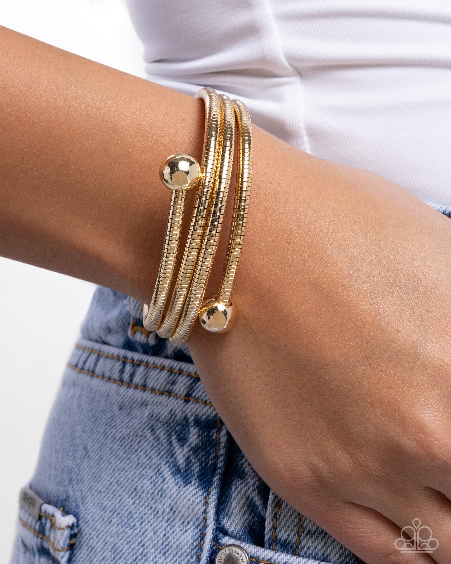 Gold bracelet on a wrist with a white background