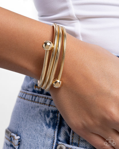Gold bracelet on a wrist with a white background