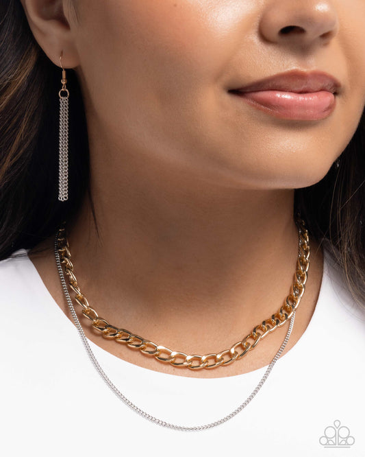 Close-up of a person wearing two necklaces and earrings on a plain background