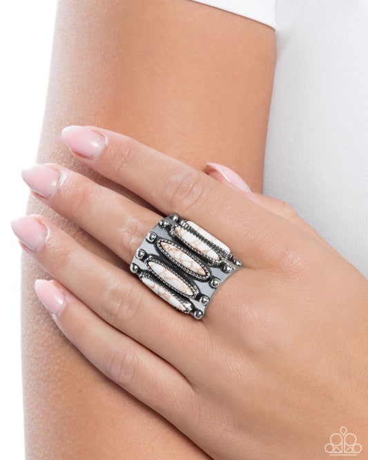 Silver ring with geometric design on a hand against a white background
