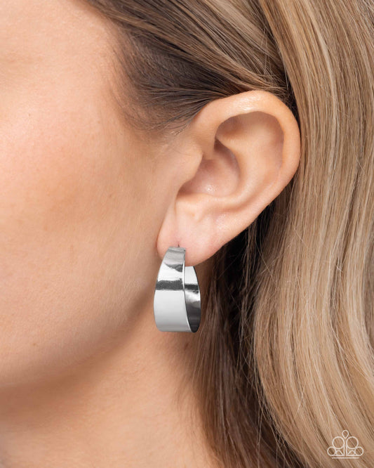 Silver hoop earring worn by a person with blonde hair.