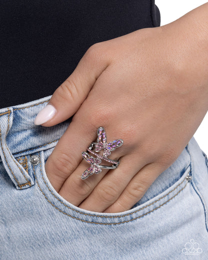 Hand wearing a star-shaped ring with pink gemstones against a denim background