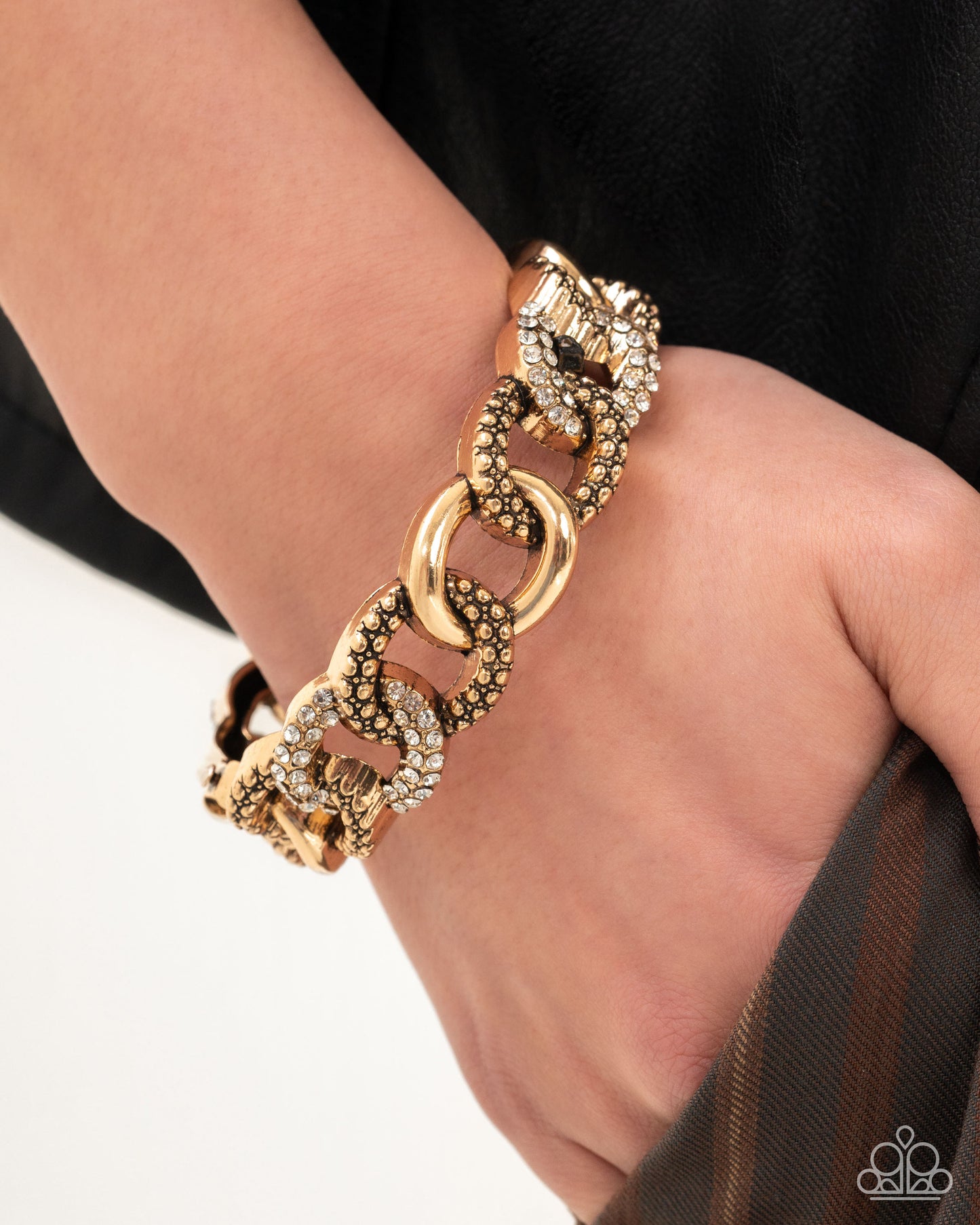 Gold chain bracelet on a wrist with a blurred background