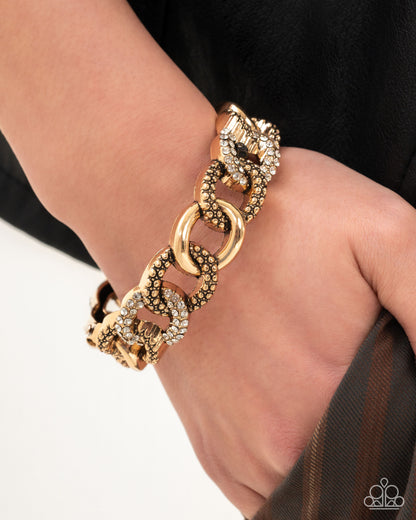 Gold chain bracelet on a wrist with a blurred background