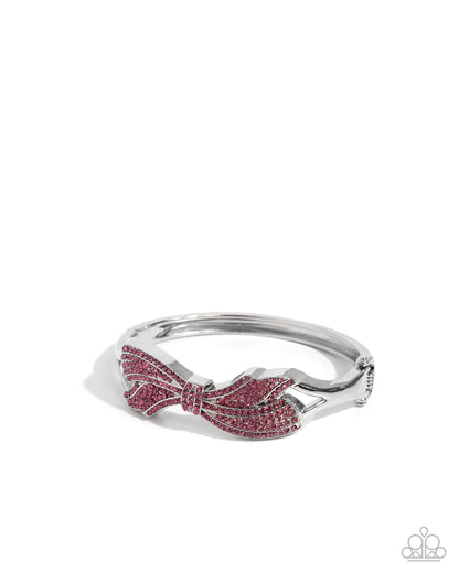Silver ring with pink gemstone bow design on a white background
