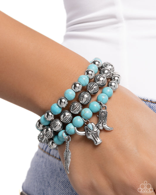 Turquoise beaded bracelet with silver charms on a wrist against a white background