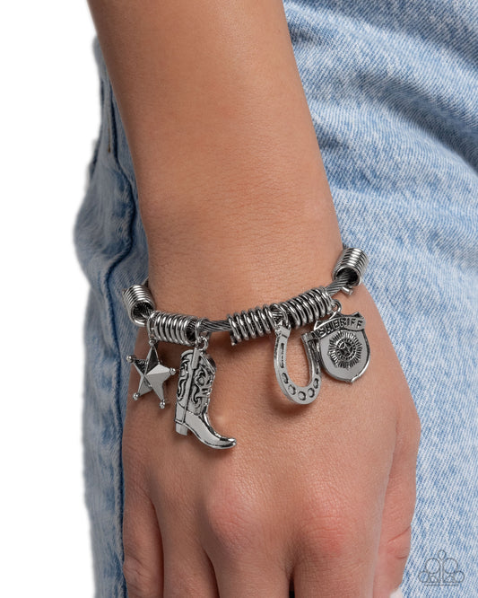 Silver charm bracelet on a wrist with denim background