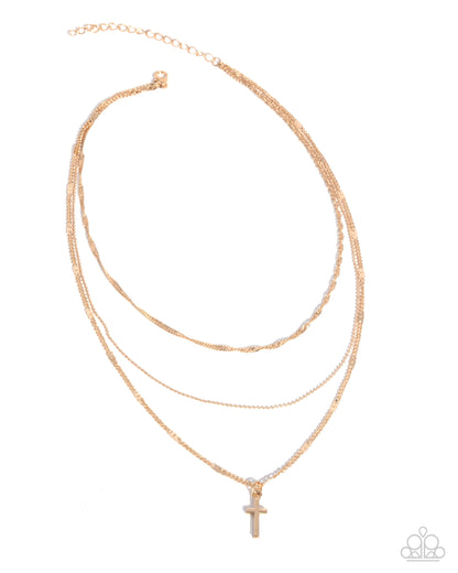 Stack of gold necklaces with a cross pendant on a white background