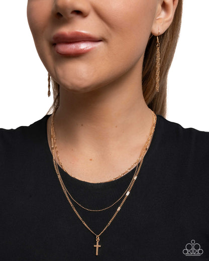 Close-up of a woman wearing gold necklaces and earrings on a plain background