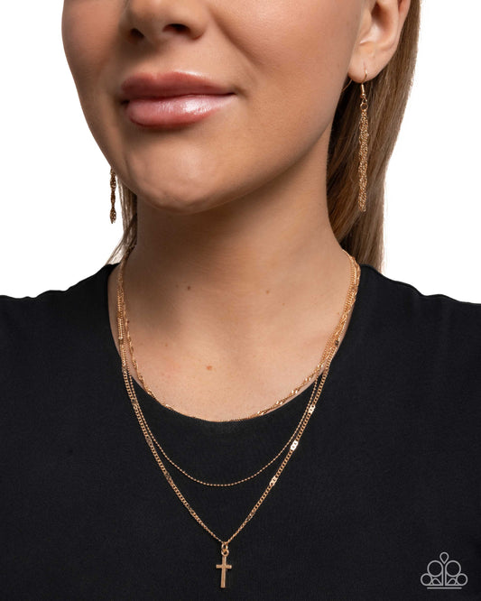 Close-up of a woman wearing gold necklaces and earrings on a plain background