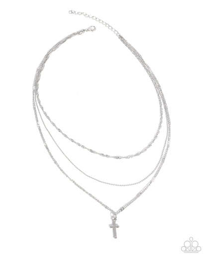 Stack of silver necklaces with a cross pendant on a white background