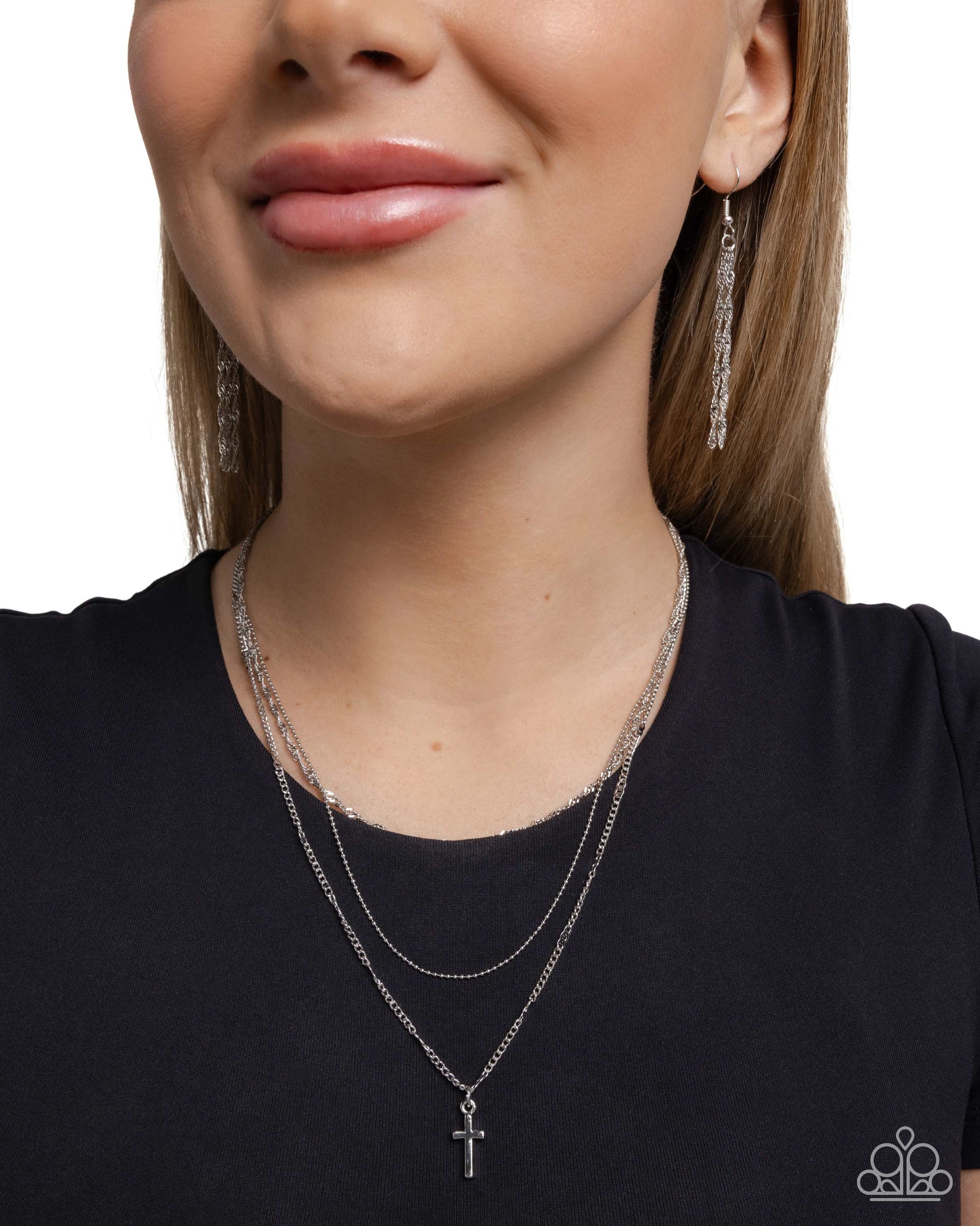 Close-up of a woman wearing silver necklaces and earrings on a white background