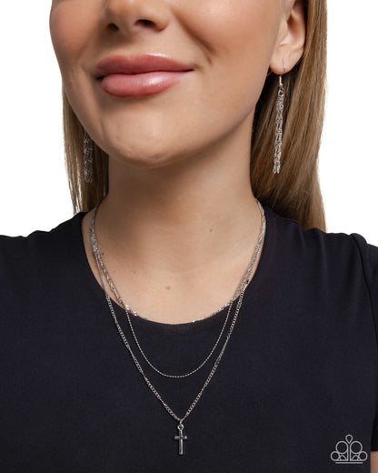 Close-up of a woman wearing silver necklaces and earrings on a white background