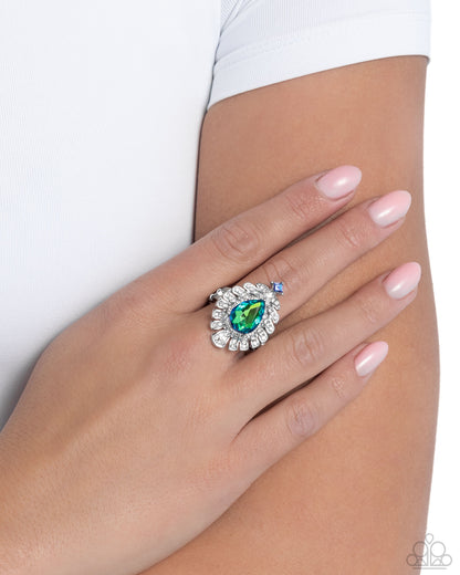Close-up of a hand wearing a decorative ring with a green gemstone on a white background