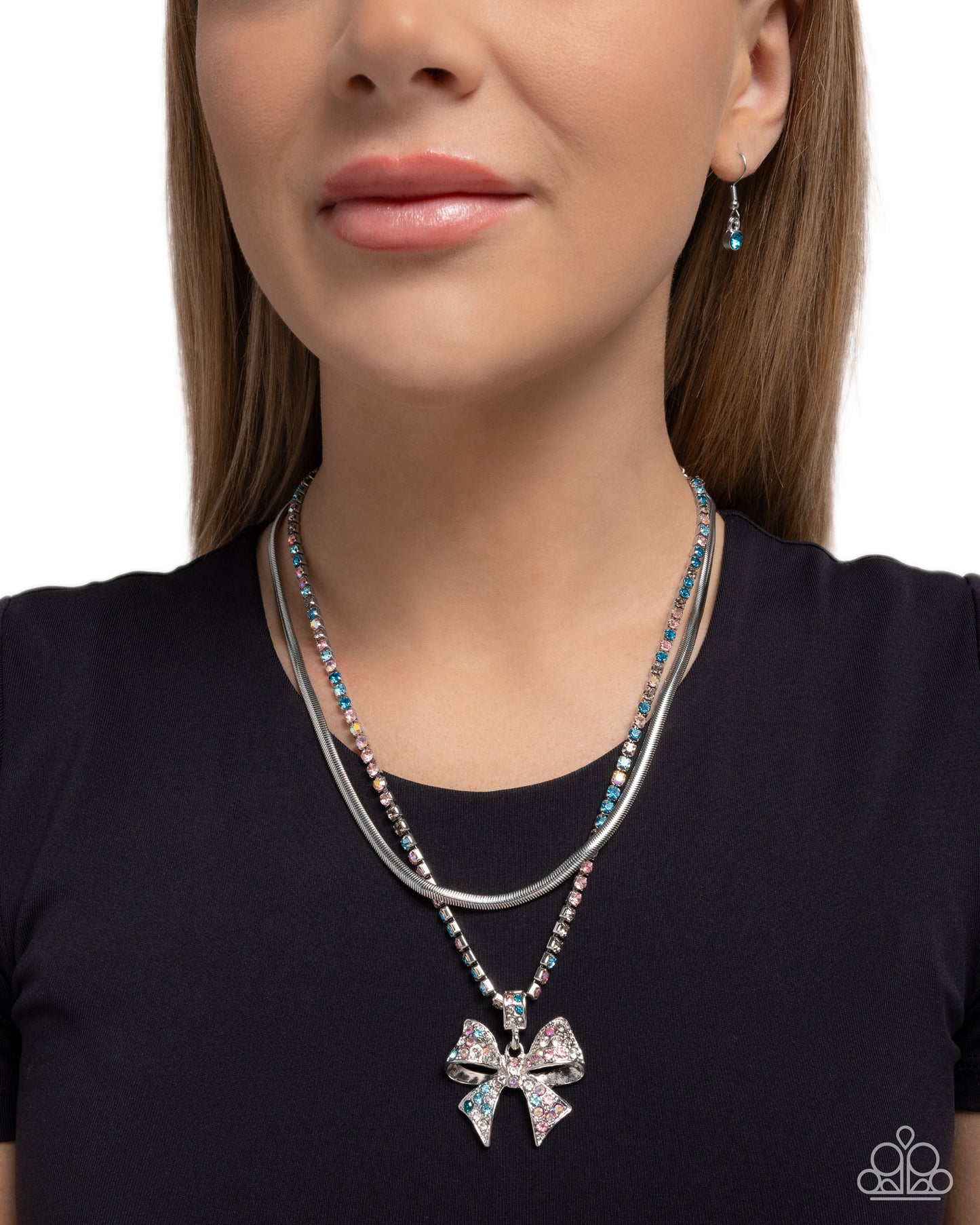 Woman wearing a silver necklace with a bow pendant on a plain background