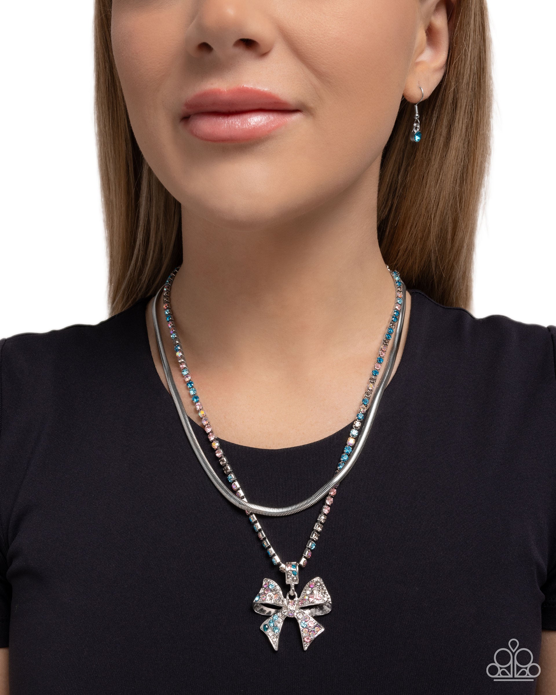 Woman wearing a silver necklace with a bow pendant on a plain background