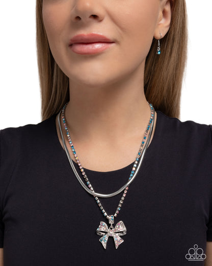 Woman wearing a silver necklace with a bow pendant on a plain background