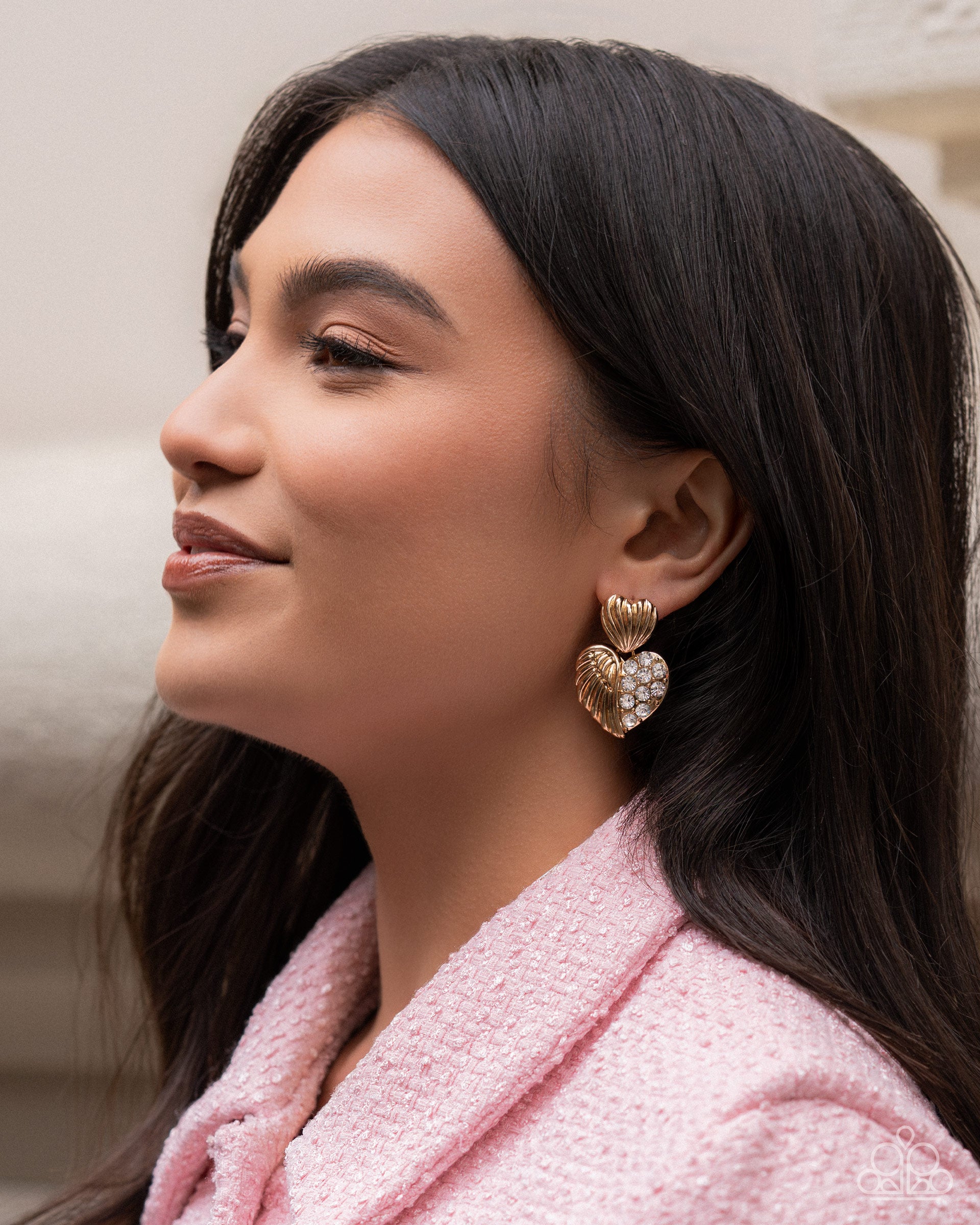 Woman wearing heart-shaped earrings with a pink coat