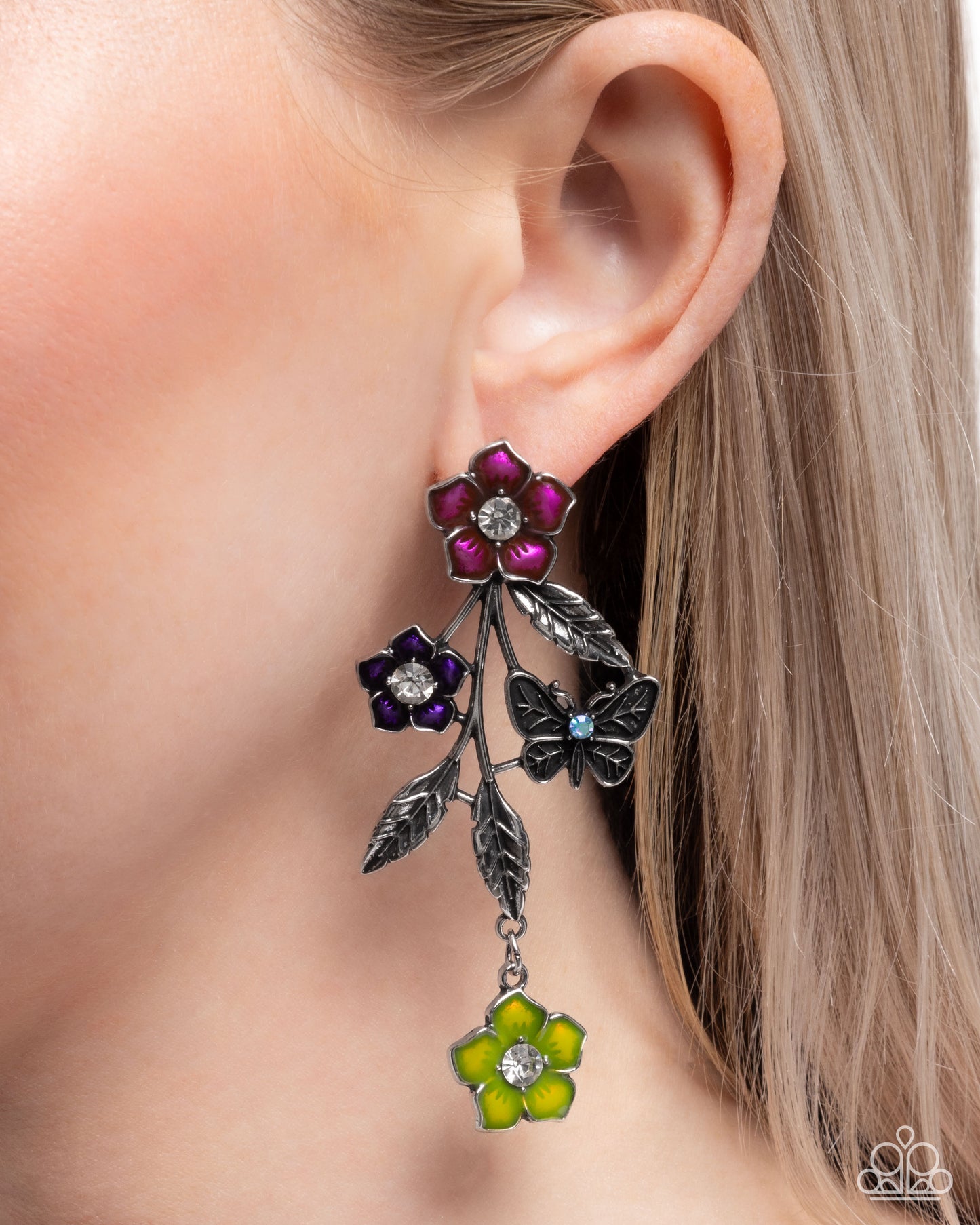 Close-up of an ear wearing a decorative earring with flowers and butterflies.