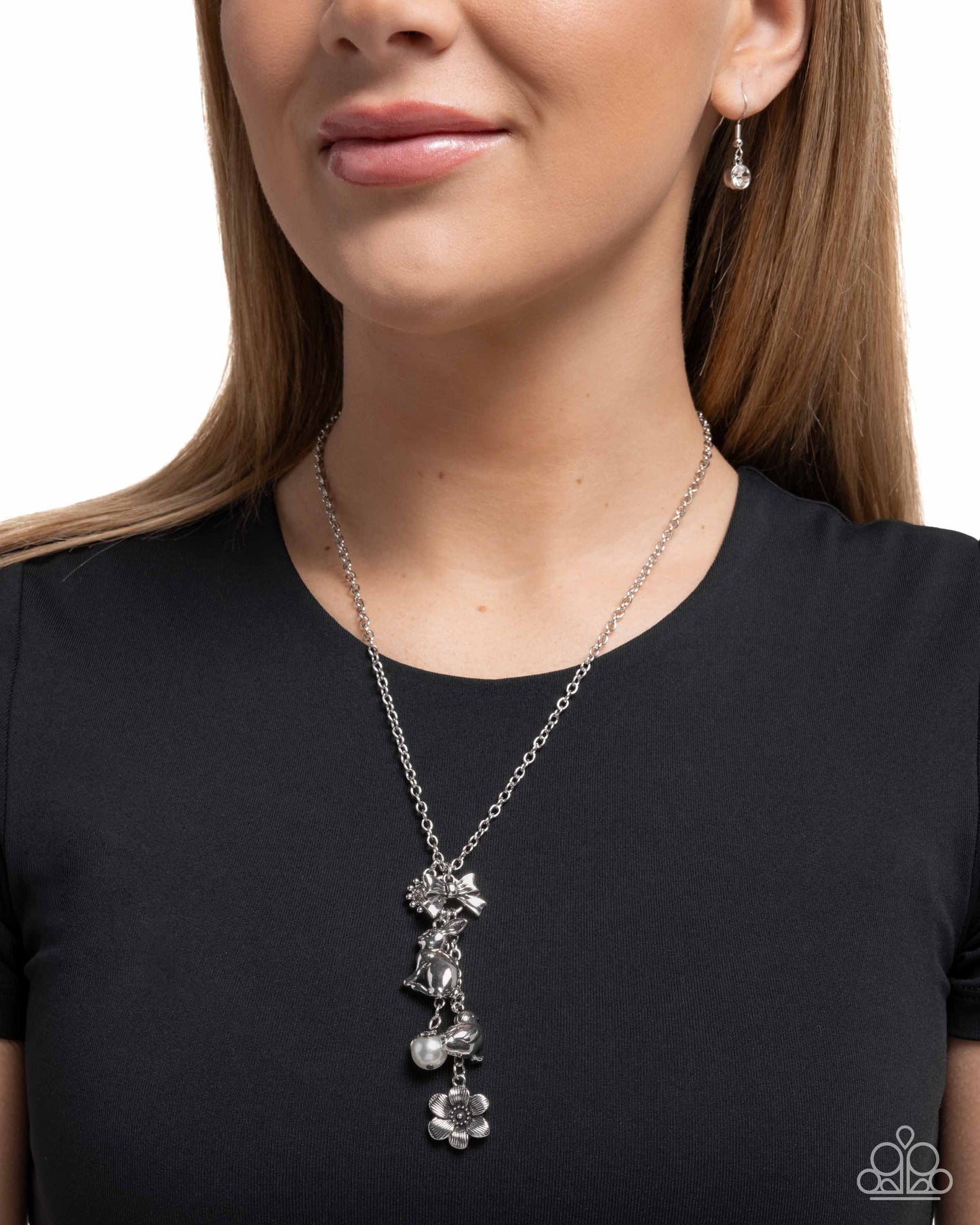 Woman wearing a silver necklace with floral pendants on a plain background