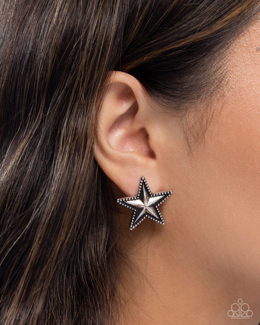 Star-shaped earring worn on an ear with dark hair.