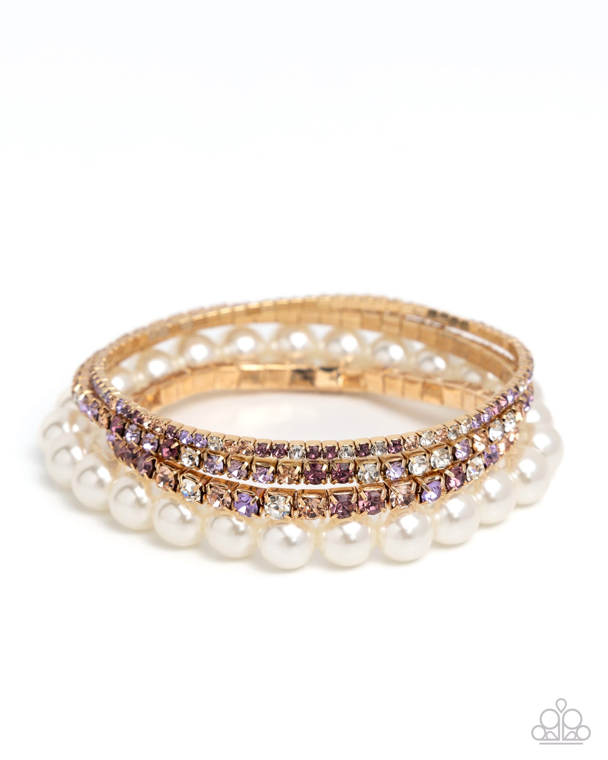 A stack of three gold bangles, featuring one row of white faux pearls, one row of clear rhinestones, and one row of lavender-purple rhinestones, displayed on a clean white background.