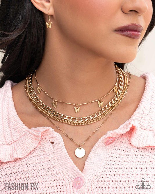 Close-up of a woman wearing multiple gold necklaces with a pink sweater.