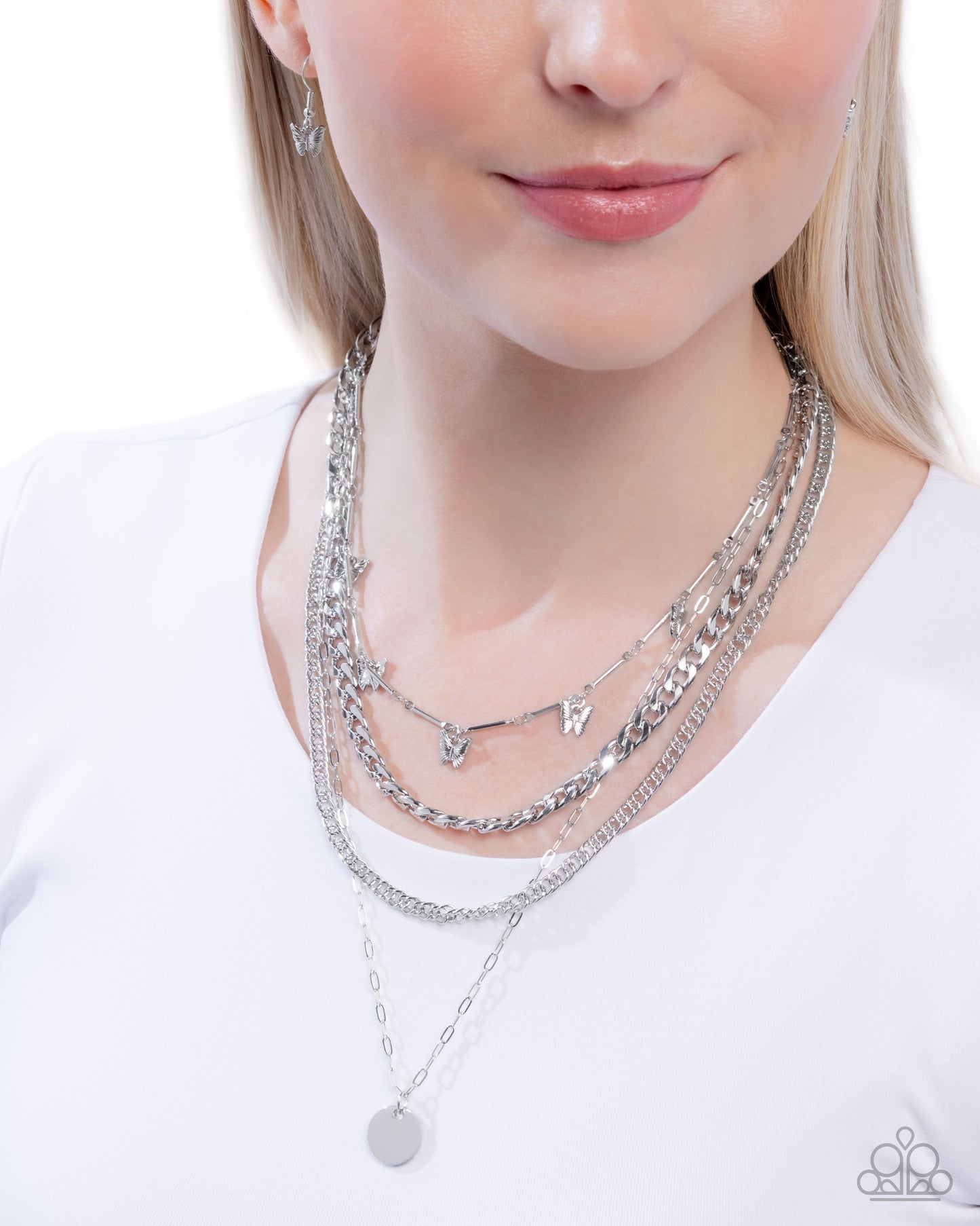Woman wearing multiple silver necklaces on a white background