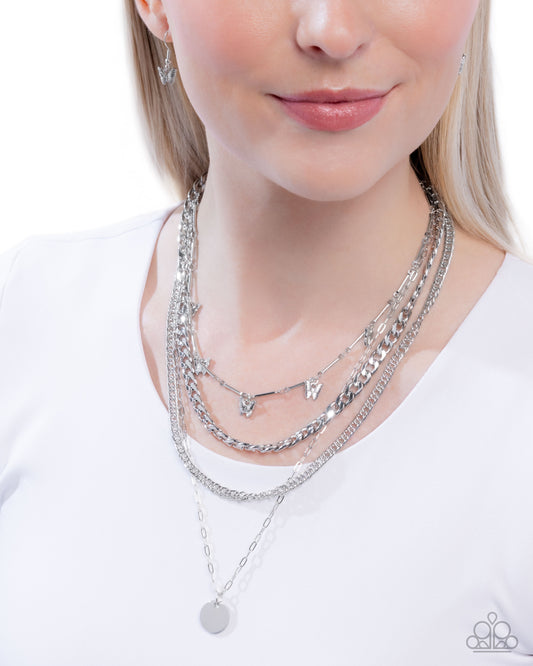 Woman wearing multiple silver necklaces on a white background