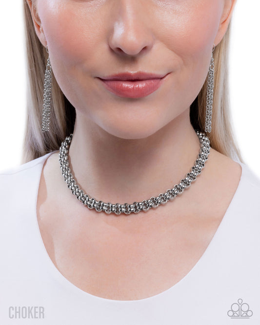 Close-up of a woman wearing a silver choker necklace and earrings.