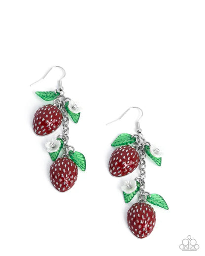 Pair of earrings with red strawberry-like charms and green leaves on a white background