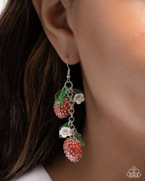 Earring with strawberry design hanging from an ear