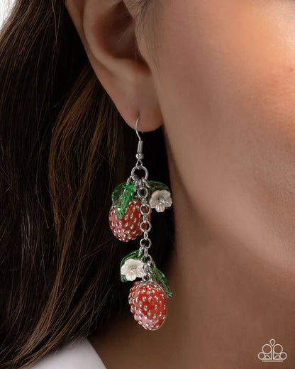 Earring with strawberry design hanging from an ear