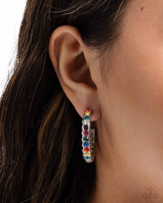 Close-up of an ear wearing a colorful hoop earring with dark hair.