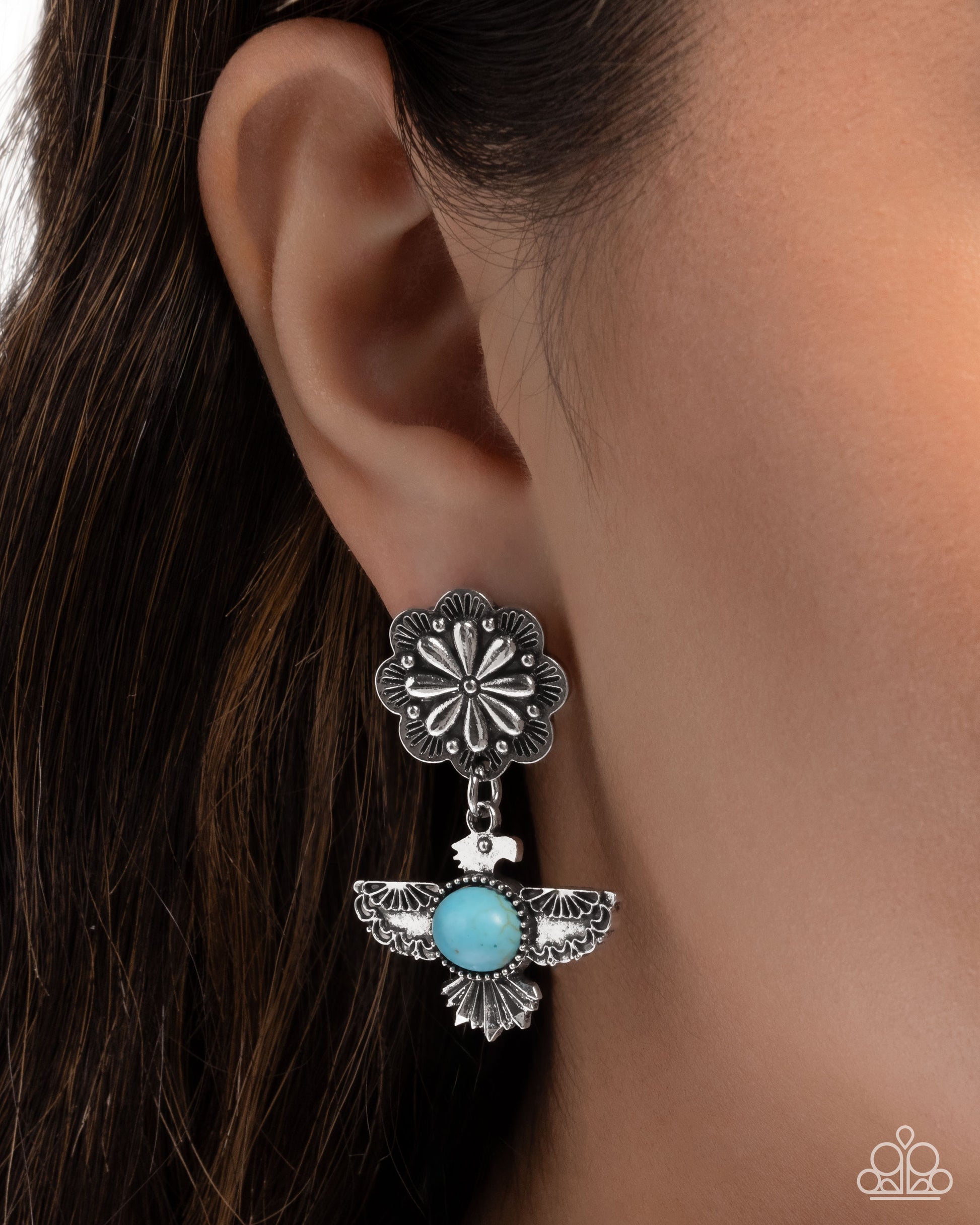 Silver floral earring with turquoise stone worn by a person