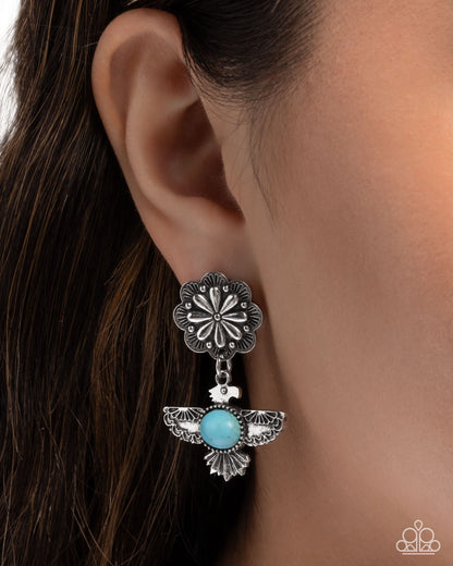 Silver floral earring with turquoise stone worn by a person