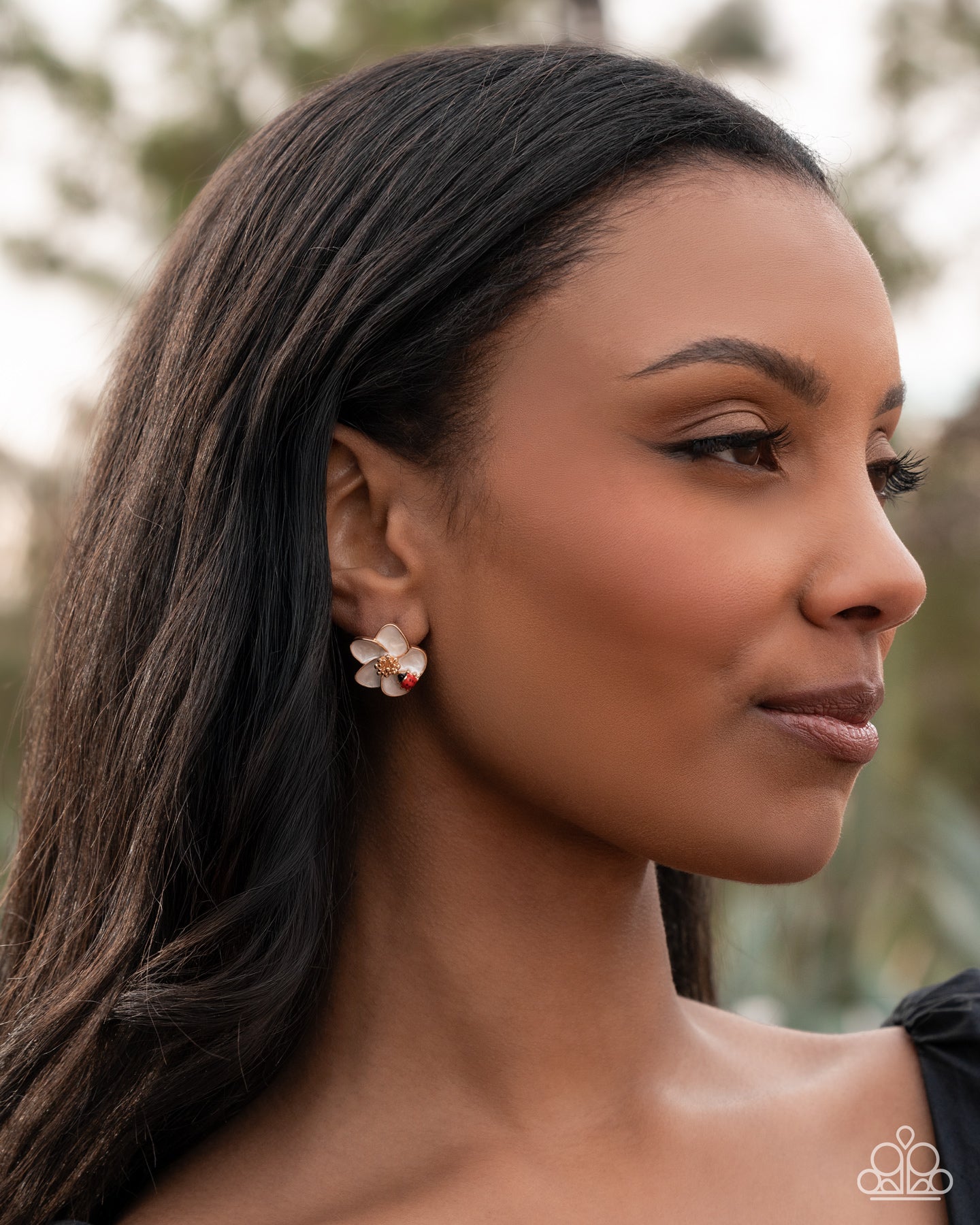 Woman wearing a floral earring with a blurred natural background