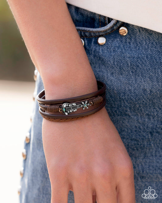 Close-up of a hand wearing multiple leather bracelets with decorative elements on a blurred background.