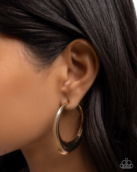 Gold hoop earring worn by a person with dark hair