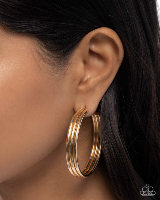 Gold hoop earrings worn by a person with dark hair.