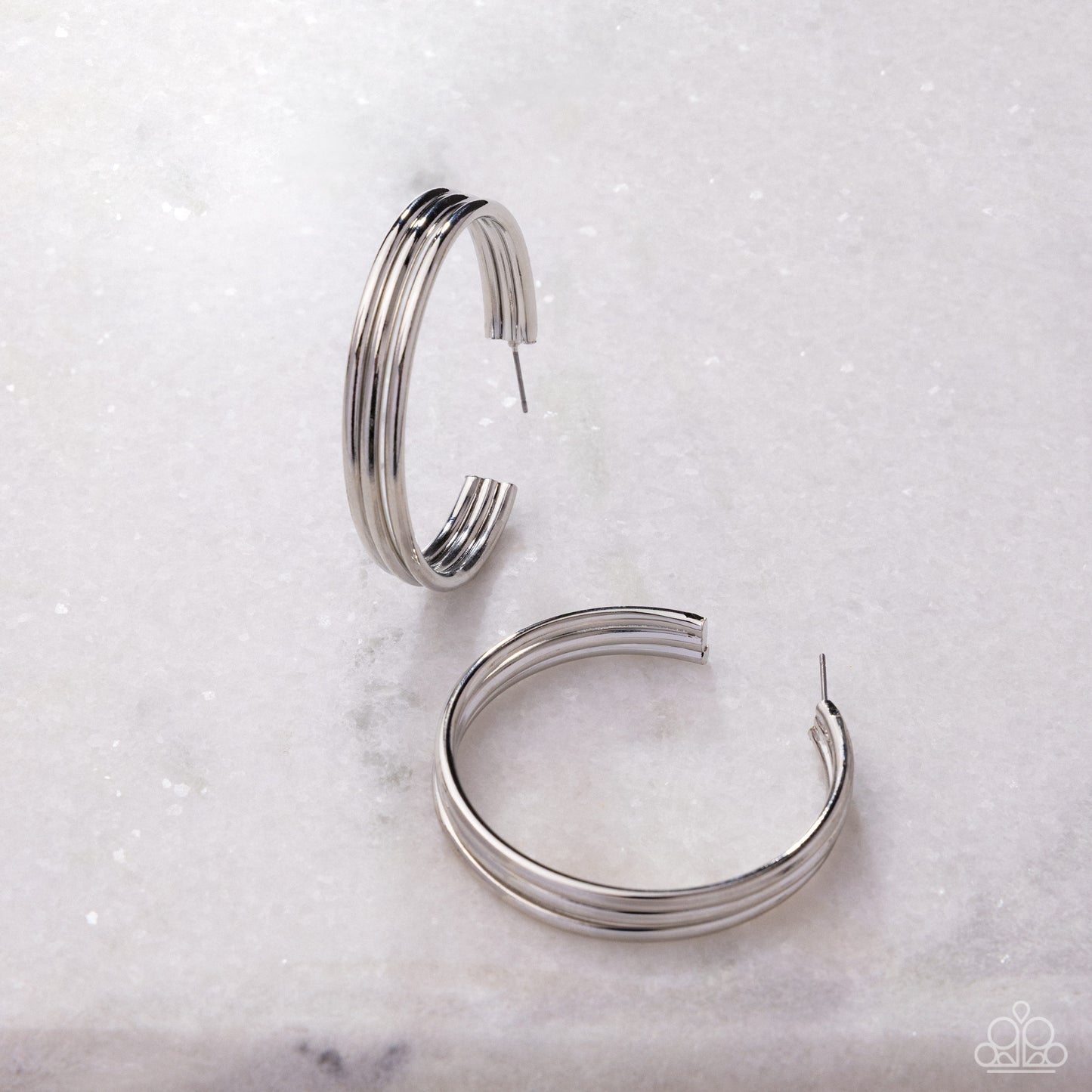 Pair of silver hoop earrings on a light marble background