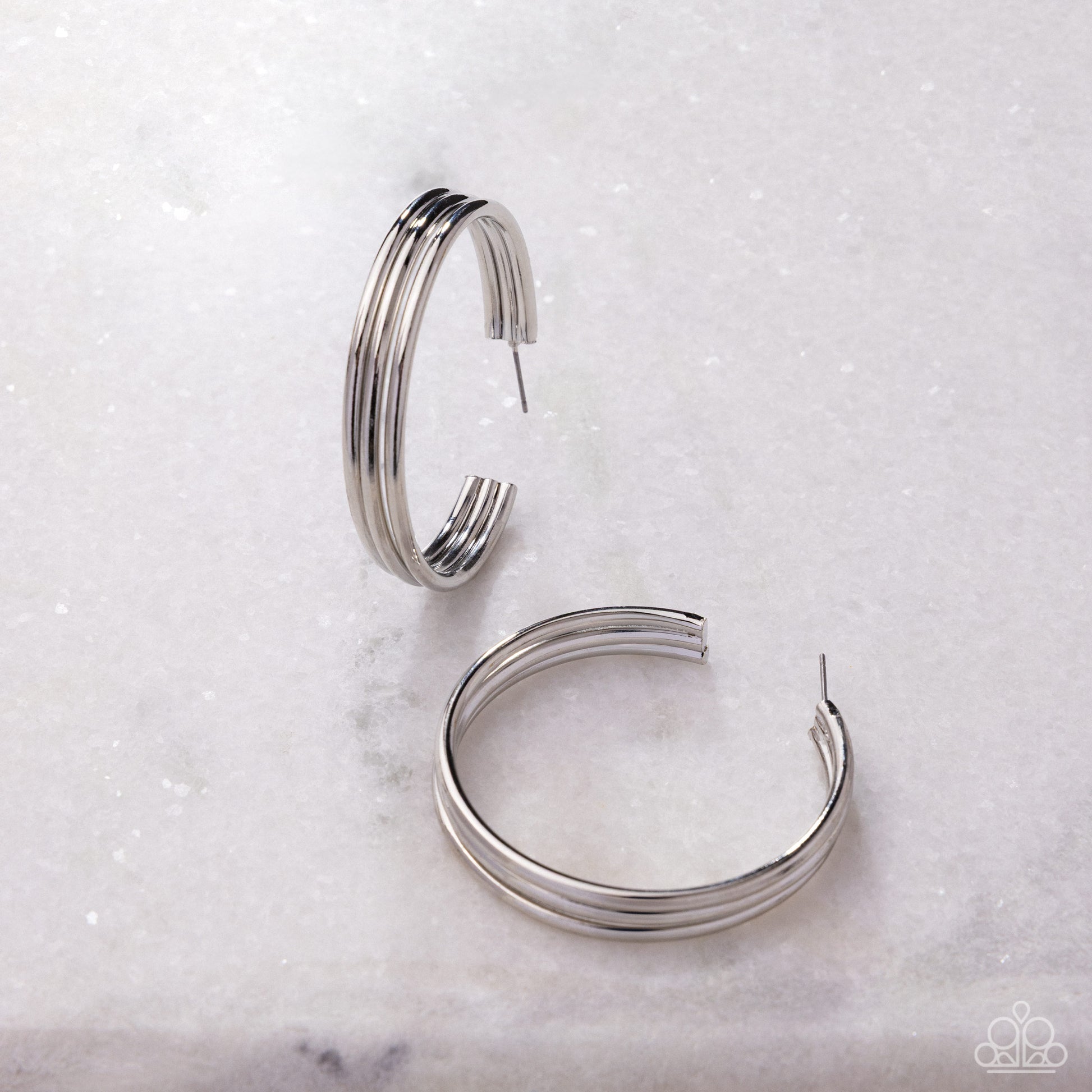 Pair of silver hoop earrings on a light marble background