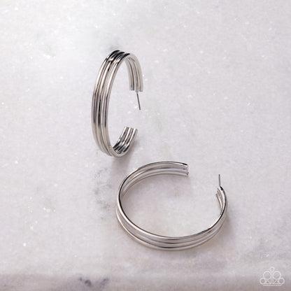 Pair of silver hoop earrings on a light marble background