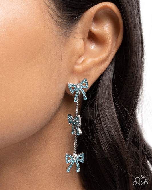 Blue bow earrings worn by a person with dark hair.