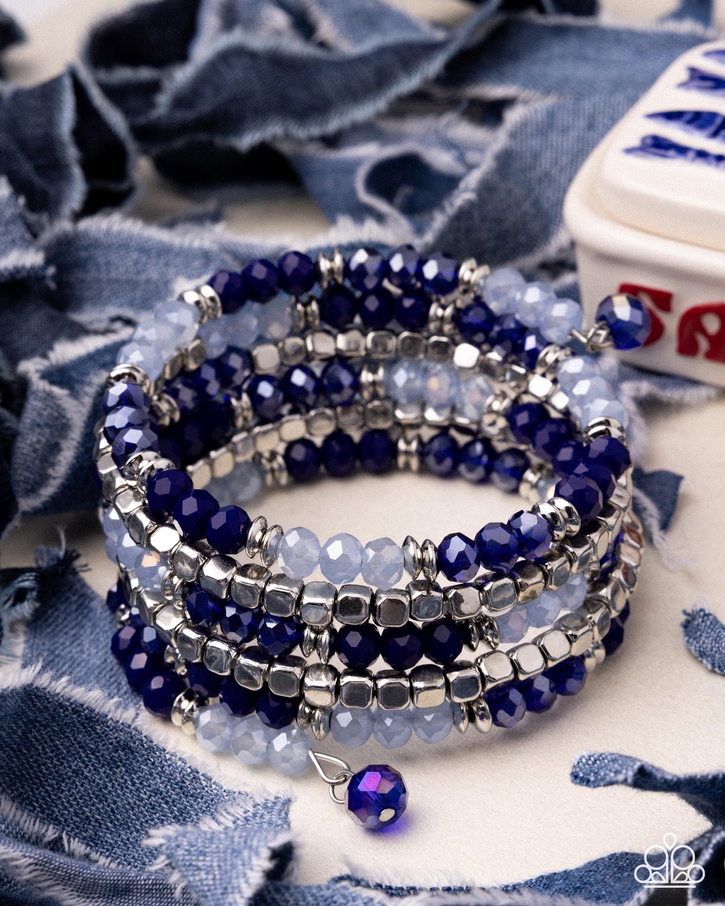Stack of blue beaded bracelets on a blue fabric background