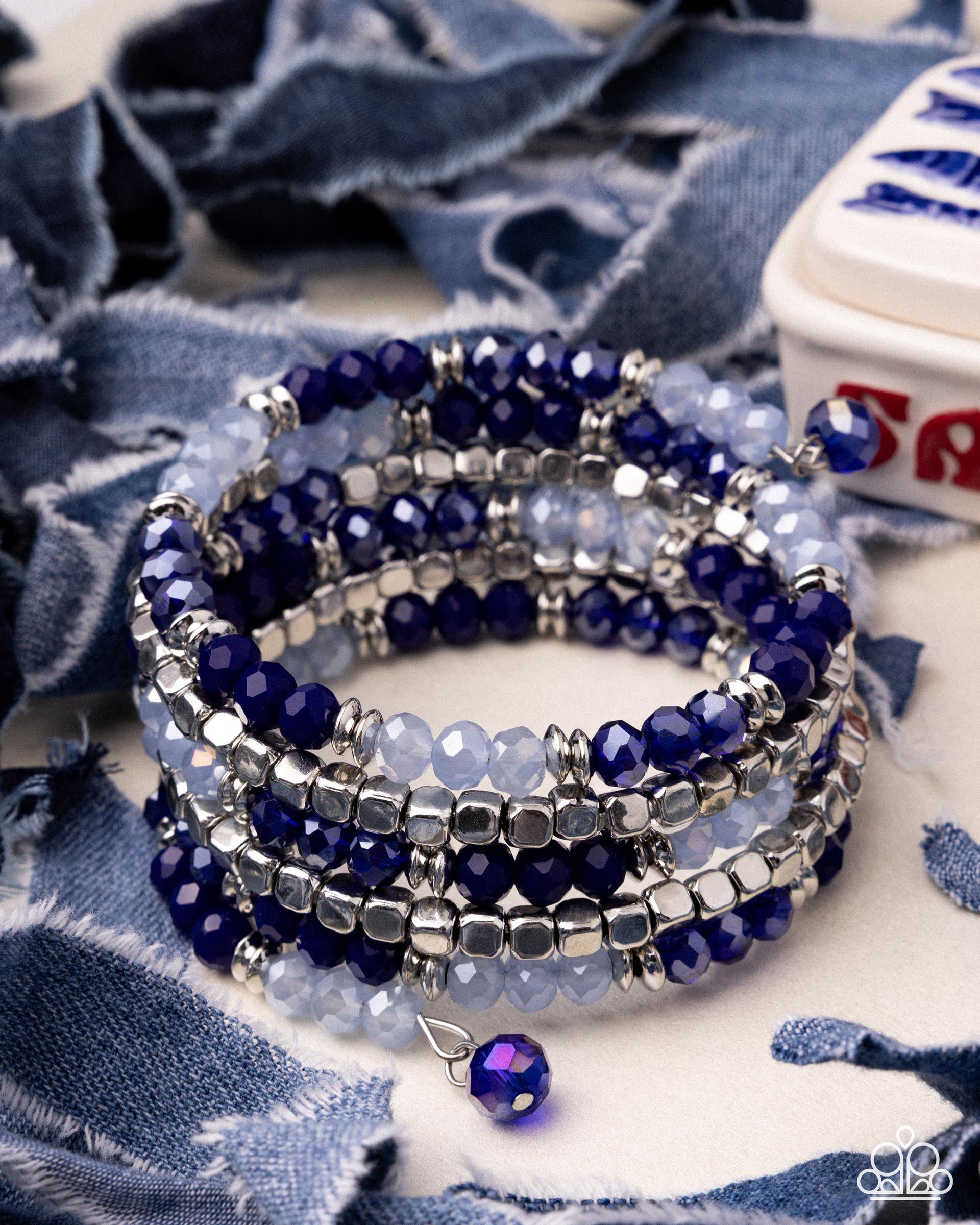 Stack of blue beaded bracelets on a blue fabric background