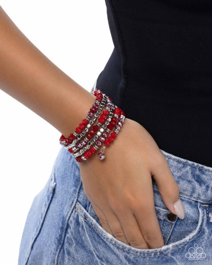 Stack of red beaded bracelets on a wrist with a black background